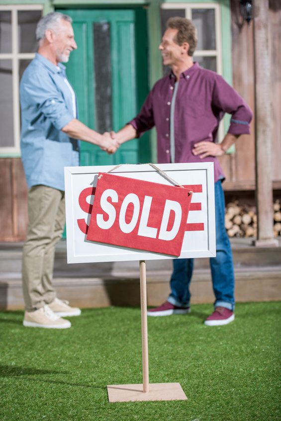 men shaking hands with saleman and buying house
